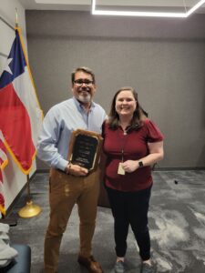 Former President Mike Wigington receives a plaque for his service from current president Lisa Holcomb.